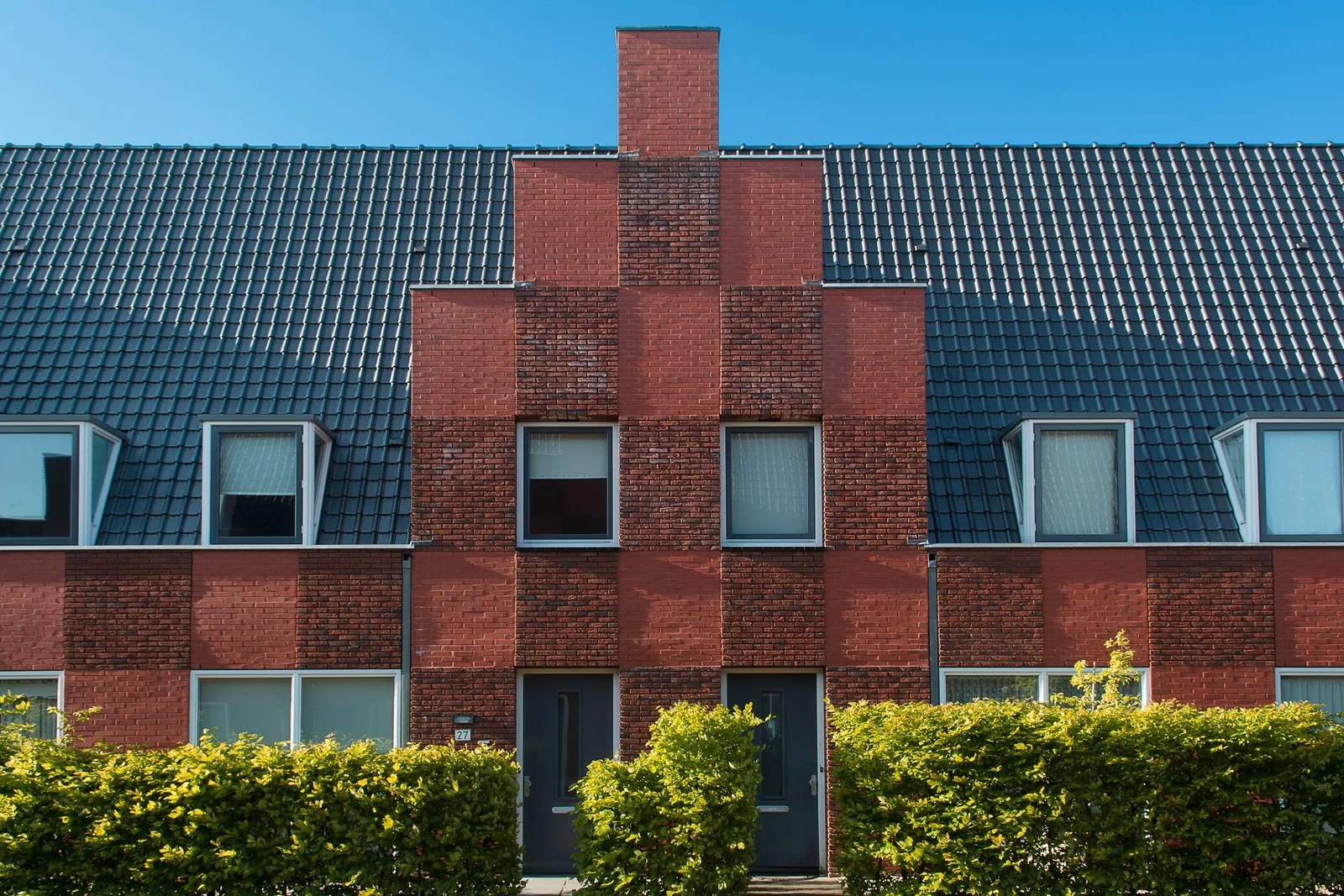 Brick housing block with a stepped gable and hedges