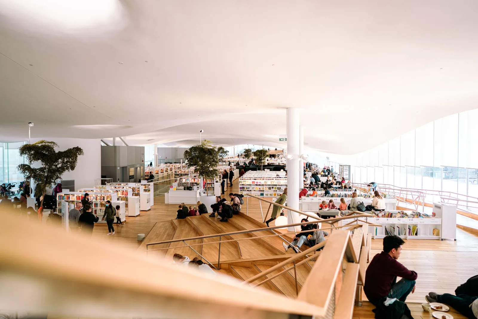 Bright open library floor with plants and people reading